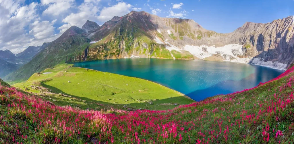 an image of ratti gali lake with its green meadows and mountains